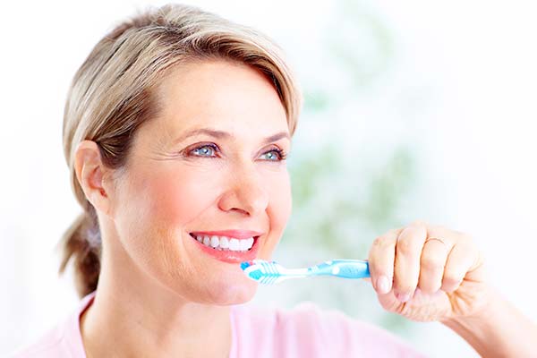 Older woman holding a blue toothbrush